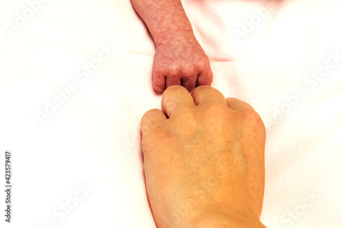 Größenvergleich zwischen der Hand eines neugeborenen Babys und der Hand der Mutter