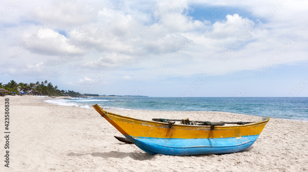 Small fishing boat on an empty tropical beach, Sri Lanka.