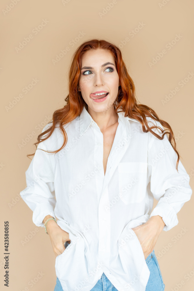 Beautiful redhead girl posing on peach color background Beautiful redhead girl posing on peach color background