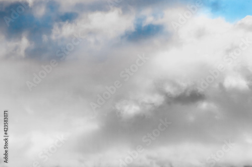 Grey and white rain-dense clouds block the blue sky. Changing weather and processes in the atmosphere