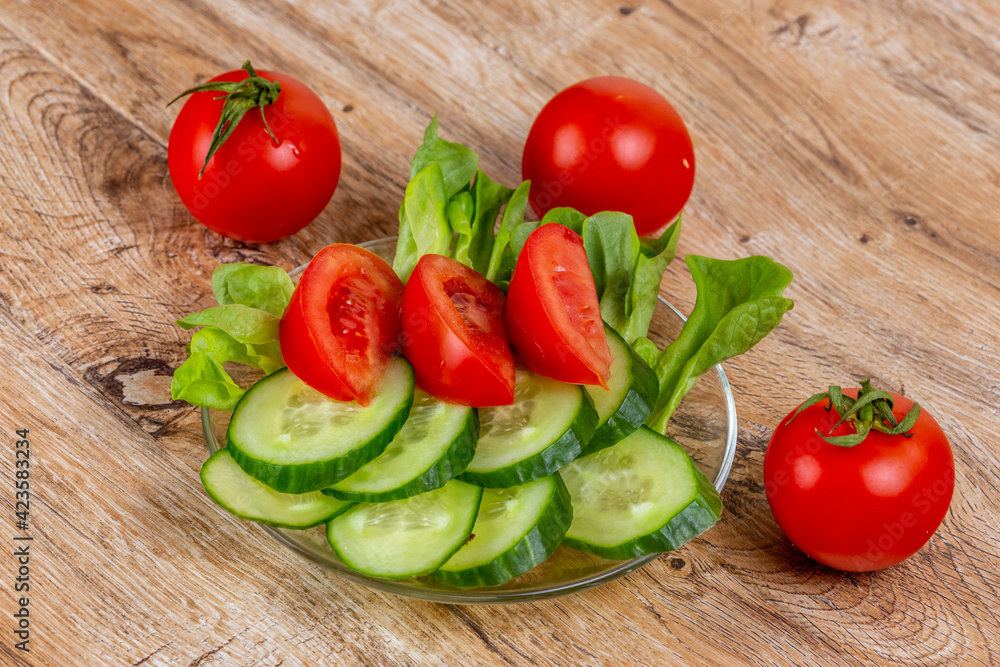Vegetable slicing of cucumbers and tomatoes on a plate on a wooden background Vegetable slicing of cucumbers and tomatoes on a plate on a wooden background