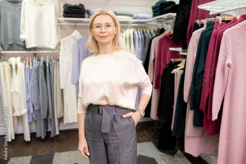 Portrait of elegant mature woman looking at camera standing in clothes store
