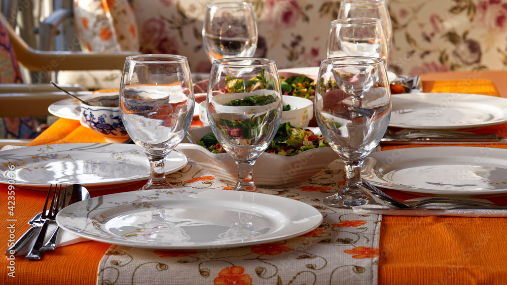 Fototapeta premium Dinner table prepared with plates, glasses, forks and spoons