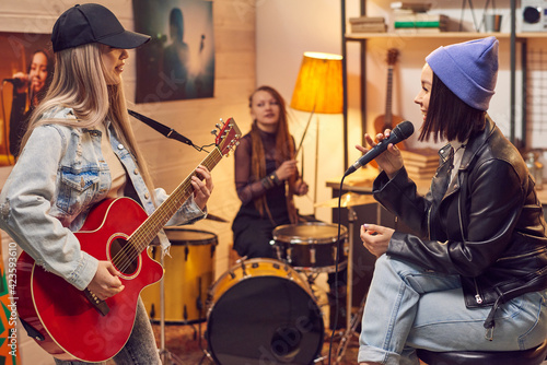 Group of young women singing and playing musical instruments during rehearsal in the studio