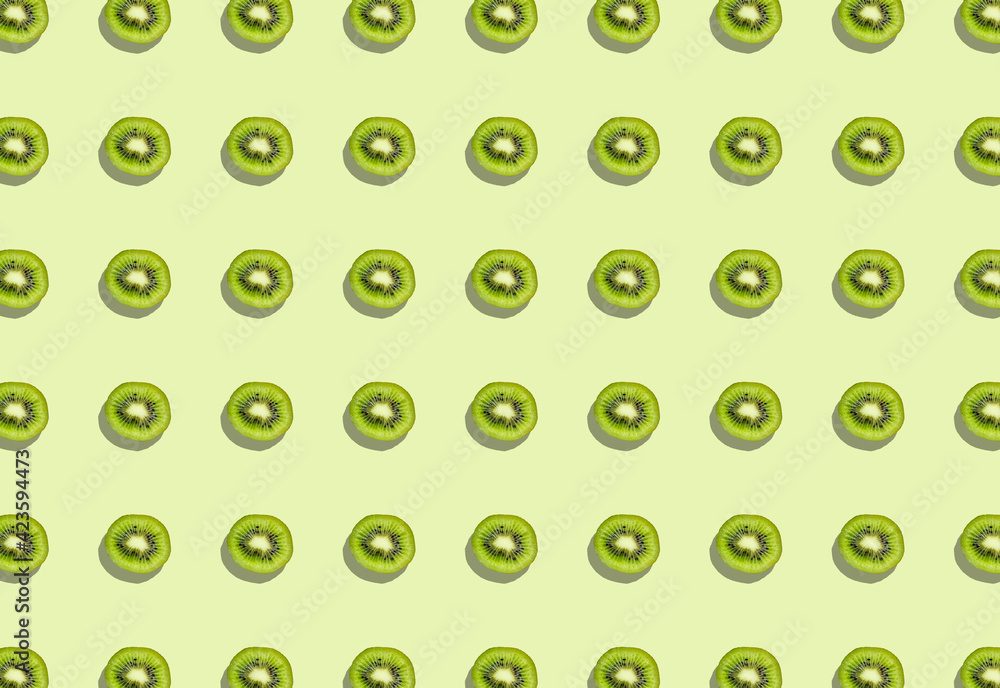 A pattern with a split kiwi with a shadow on a green background. A pattern with a split kiwi with a shadow on a green background.