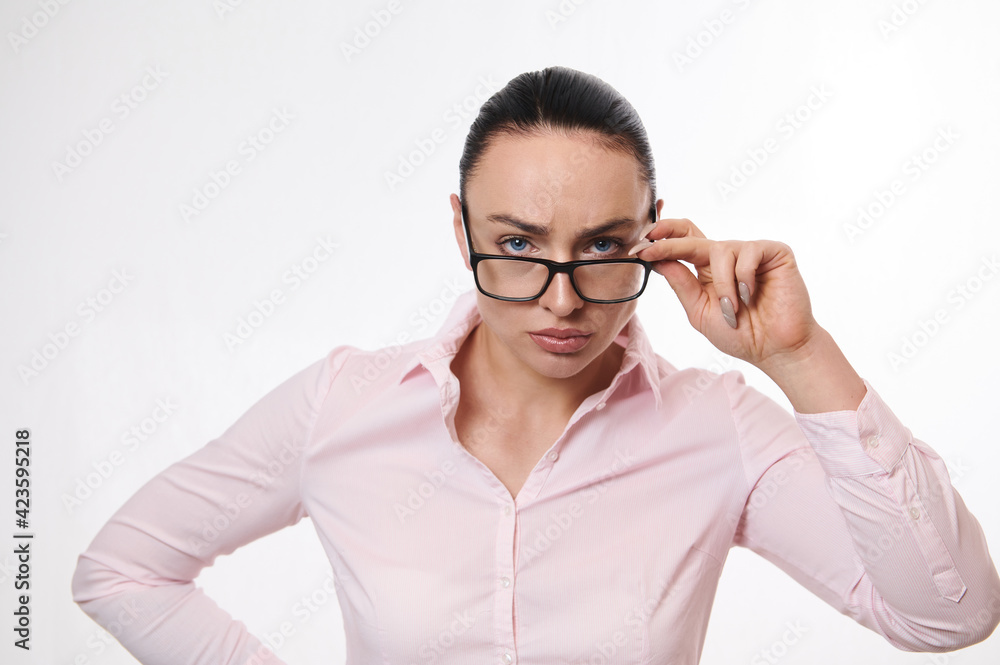 Strict and serious woman in business casual clothes, looking at the camera through lowered glasses. Isolated portrait on white background Strict and serious woman in business casual clothes, looking at the camera through lowered glasses. Isolated portrait on white background