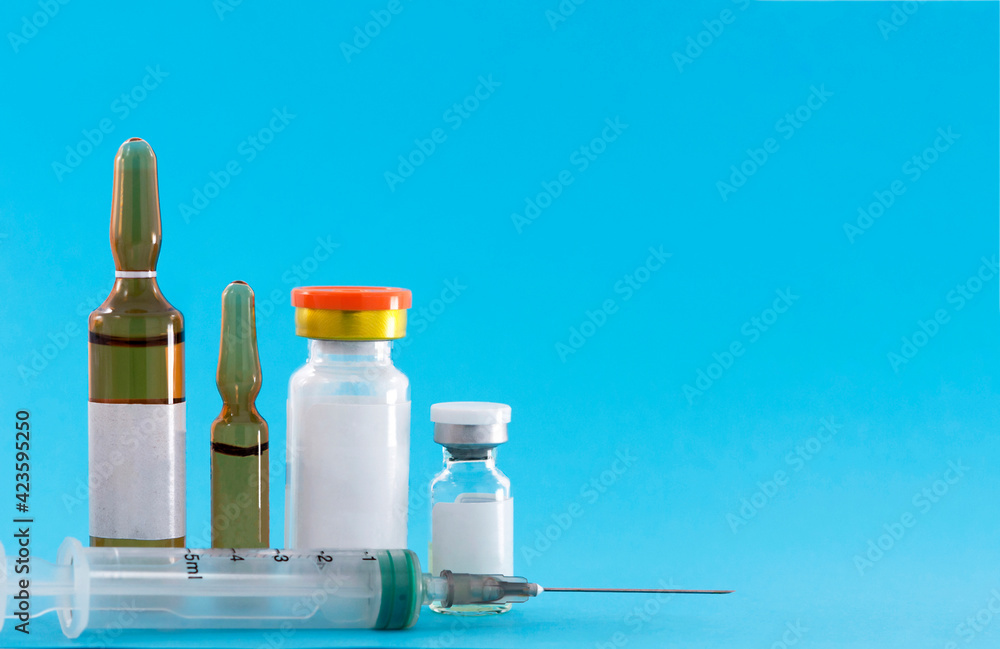 Medicine, four ampoules and a syringe on a blue background Medicine, four ampoules and a syringe on a blue background