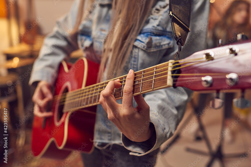 Obraz premium Close-up of woman learning to play electric guitar during musical lesson in studio