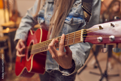 Close-up of woman learning to play electric guitar during musical lesson in studio