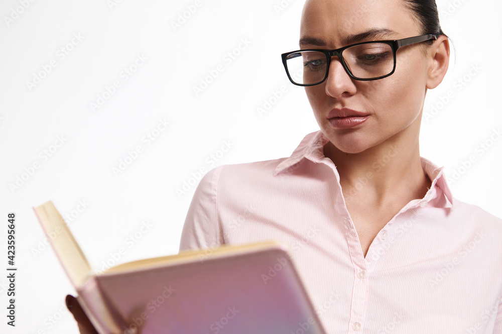 Closeup portrait of a serious and strict businessperson wearing eyeglasses, reading a book or diary. Concept of busy manager on white background with copy space Closeup portrait of a serious and strict businessperson wearing eyeglasses, reading a book or diary. Concept of busy manager on white background with copy space