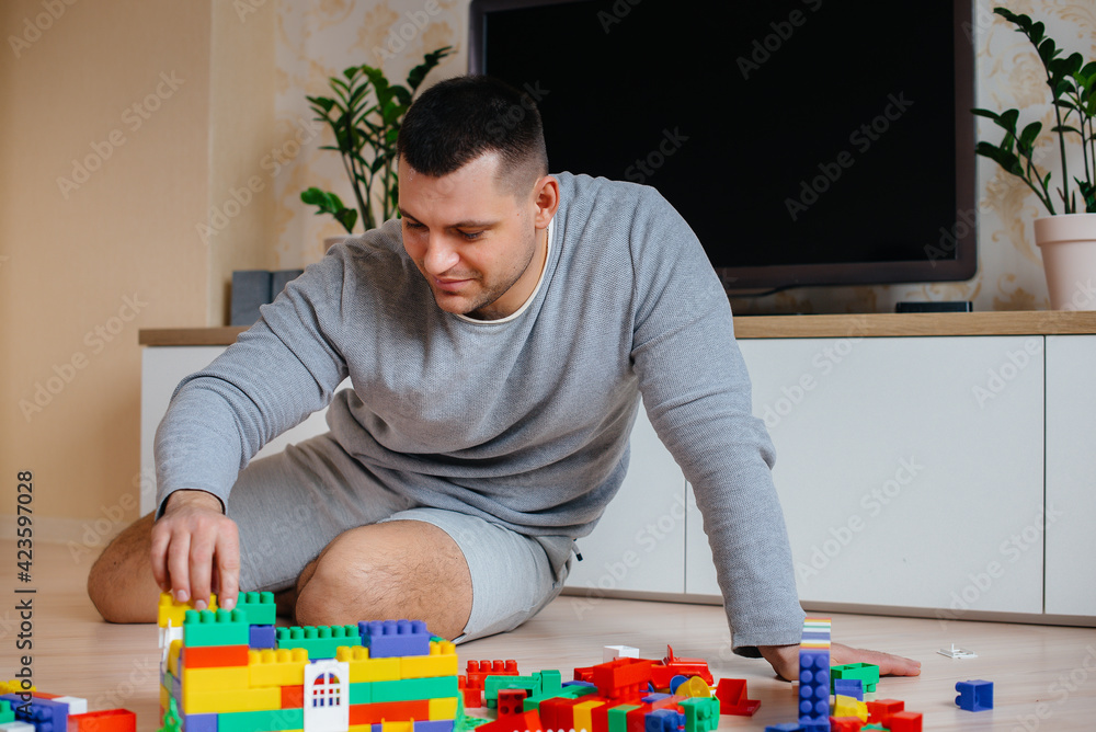 Fototapeta premium A little boy together with his father is played by a constructor and builds a house. Construction of a family home.