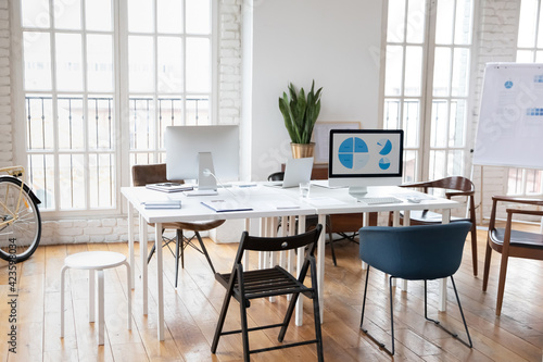 Картината върху платно Empty modern office with coworking desk and flip chart for presentation, no people around