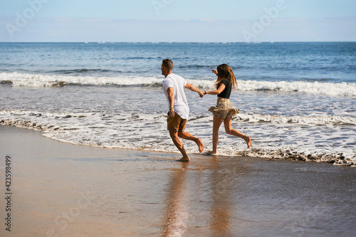 Happy young couple running on the shore of the beach, summer vacation travel. Lifestyle and summer