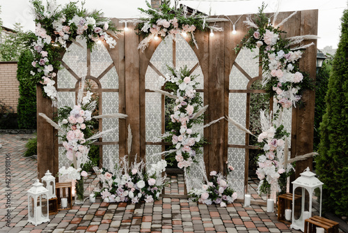 a large wooden wedding photo zone decorated with flowers. wooden wedding arch with windows. wedding decor. holiday photo zone for guests © Vadym