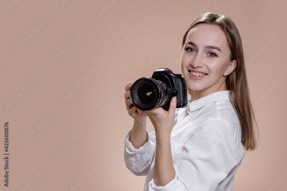 Portrait of young female photographer with copy space. Photographer with professional camera taking photo in photo studio. Profession, occupation, self-employment.