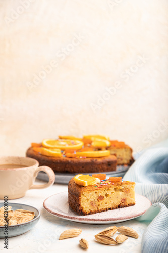 Orange cake with almonds and a cup of coffee on a white concrete background. Top view, selective focus, copy space.