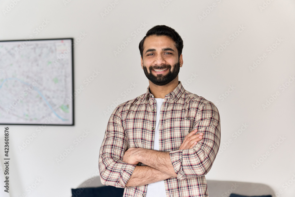 Portrait of young happy indian business man looking at camera standing with arms crossed at home office. Eastern confident male professional, smiling student, ethnic bearded entrepreneur, headshot. - obrazy, fototapety, plakaty 