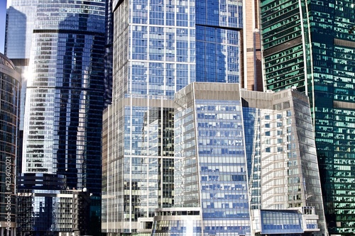 Office and residential skyscrapers in bright sun lights against clear blue sky. Commercial real estate development. Modern business and Financial city district. High buildings in modern city downtown.