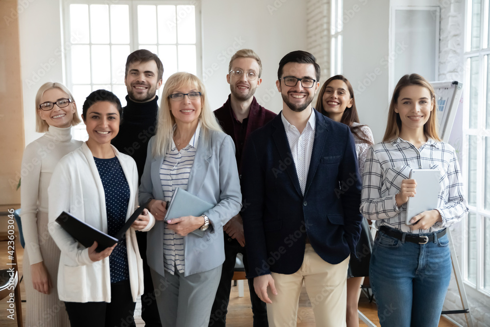 Group portrait of smiling diverse multiracial businesspeople stand pose in modern office show unity and leadership. Happy multiethnic colleagues coworkers at workplace. Teamwork, partnership concept. Group portrait of smiling diverse multiracial businesspeople stand pose in modern office show unity and leadership. Happy multiethnic colleagues coworkers at workplace. Teamwork, partnership concept.