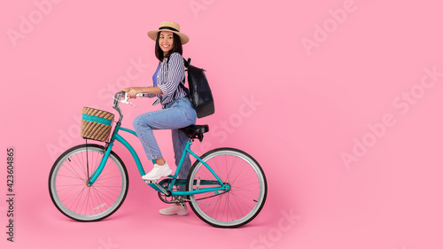 Fototapeta Naklejka Na Ścianę i Meble -  Asian woman riding retro bicycle with wicker basket, banner