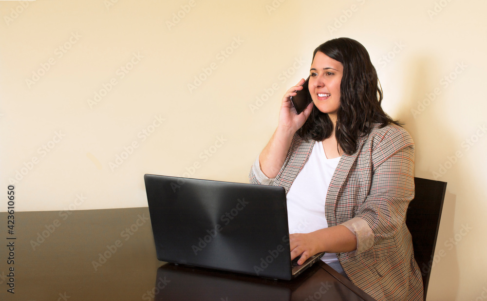 businesswoman plus size working on laptop while is talking on the phone in a office. bussines concept businesswoman plus size working on laptop while is talking on the phone in a office. bussines concept
