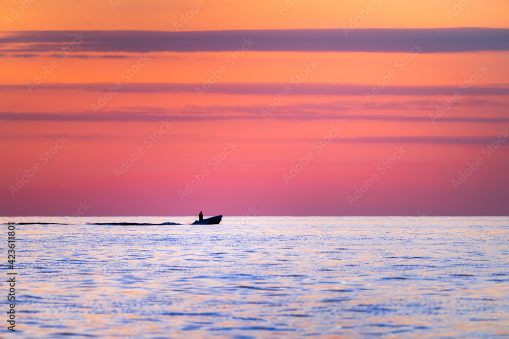 Motorboat sailing solo at sea during sunset
