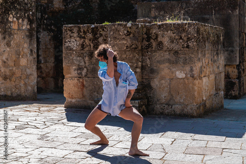 Photography Spanish man with curly hairs wearing a mask and dancing barefoot