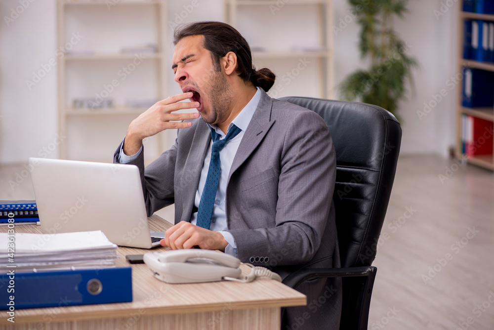 Young male employee unhappy with excessive work in the office