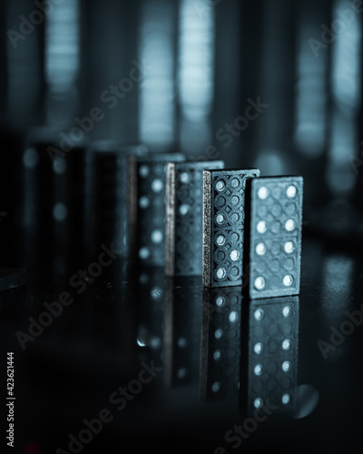 Dramatic creative image of dominos with a dark and blurry bokeh background