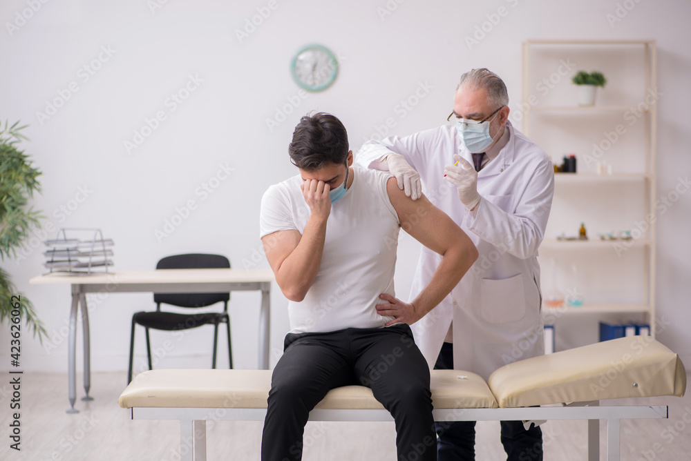 Young male patient visiting old male doctor in vaccination conce Young male patient visiting old male doctor in vaccination conce