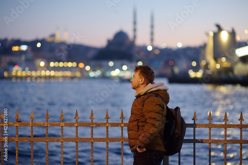 Handsome mature man on a coast of the Golden Horn bay in Istanbul, Turkey in the evening. Suleymaniye mosque and New mosque in Sultanahmet district. Travel and sightseeing spots in Asia. photo