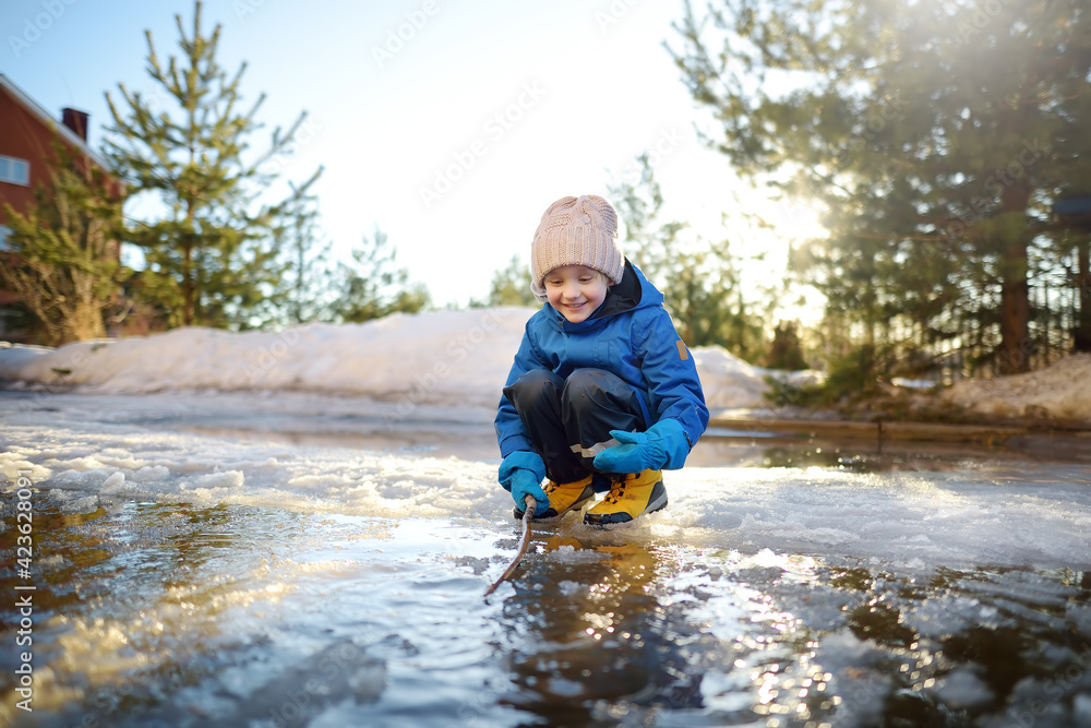 Cute preschooler boy is playing with a stick in brook on sunny day. Child having fun and enjoy a big puddle. All kids love play with water. Happy childhood. Outdoor activity for baby in sping Cute preschooler boy is playing with a stick in brook on sunny day. Child having fun and enjoy a big puddle. All kids love play with water. Happy childhood. Outdoor activity for baby in sping