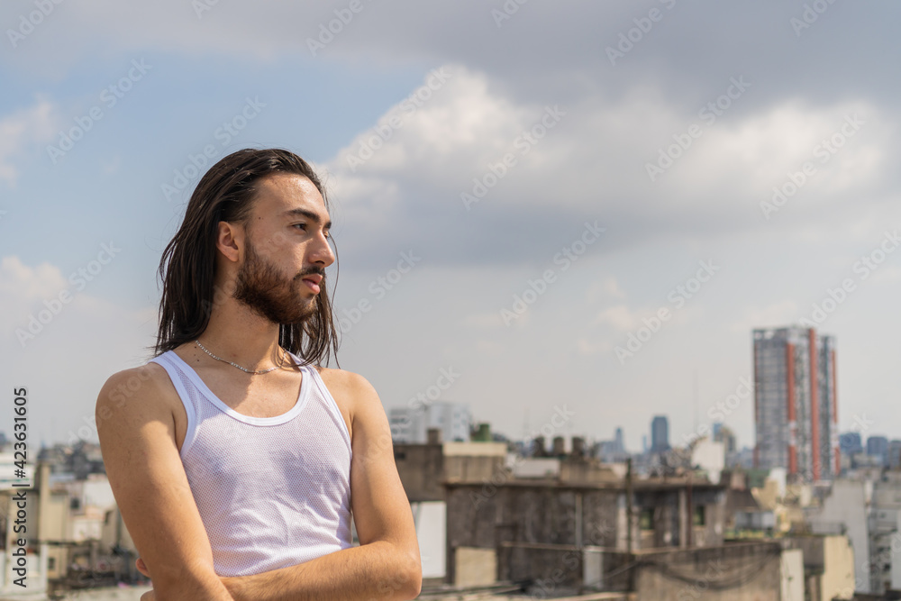 young man looking at the city from an urban rooftop, with the city and the sky in the background