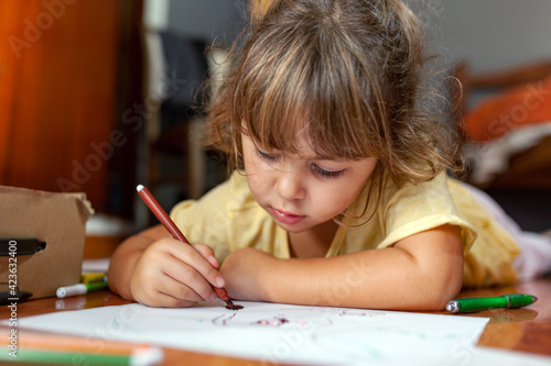 preschool girl drawing on the floor of the house