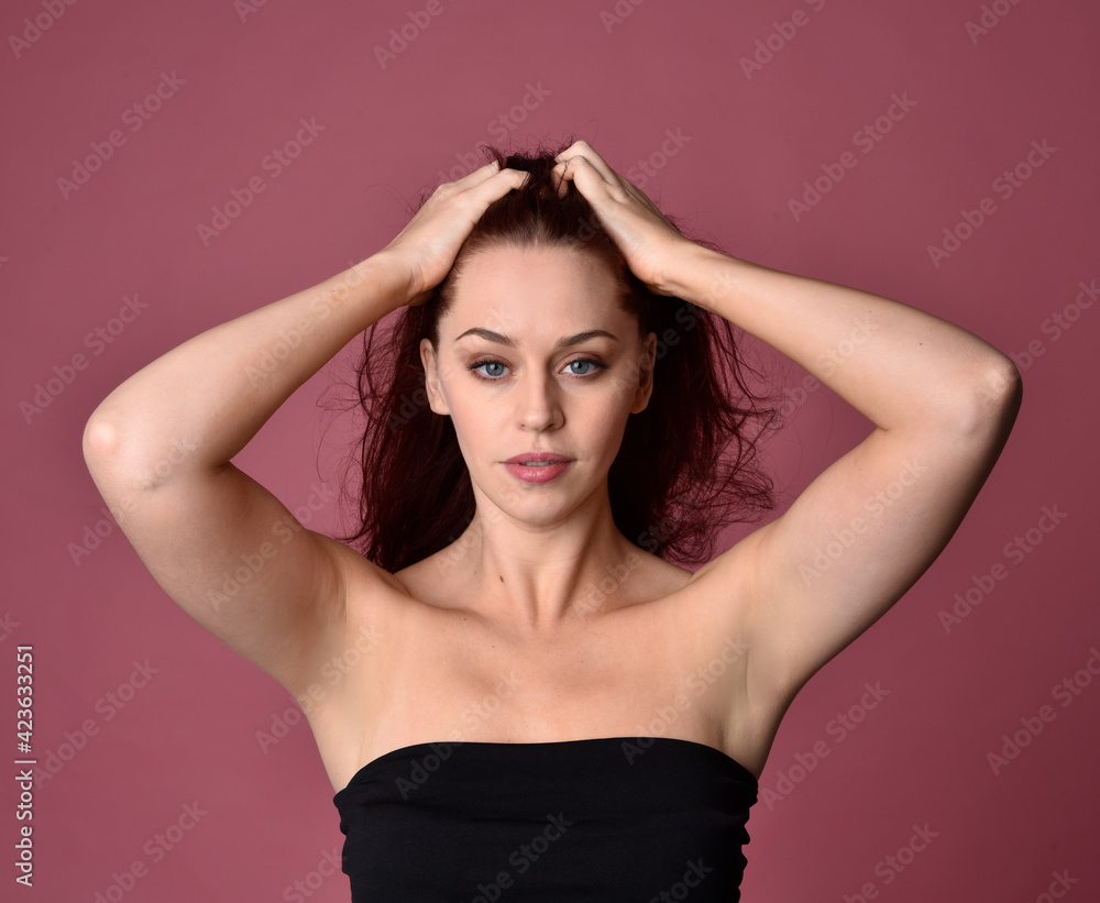 Close up portrait of a red haired woman with expressive facial features on a pink studio background. Close up portrait of a red haired woman with expressive facial features on a pink studio background.