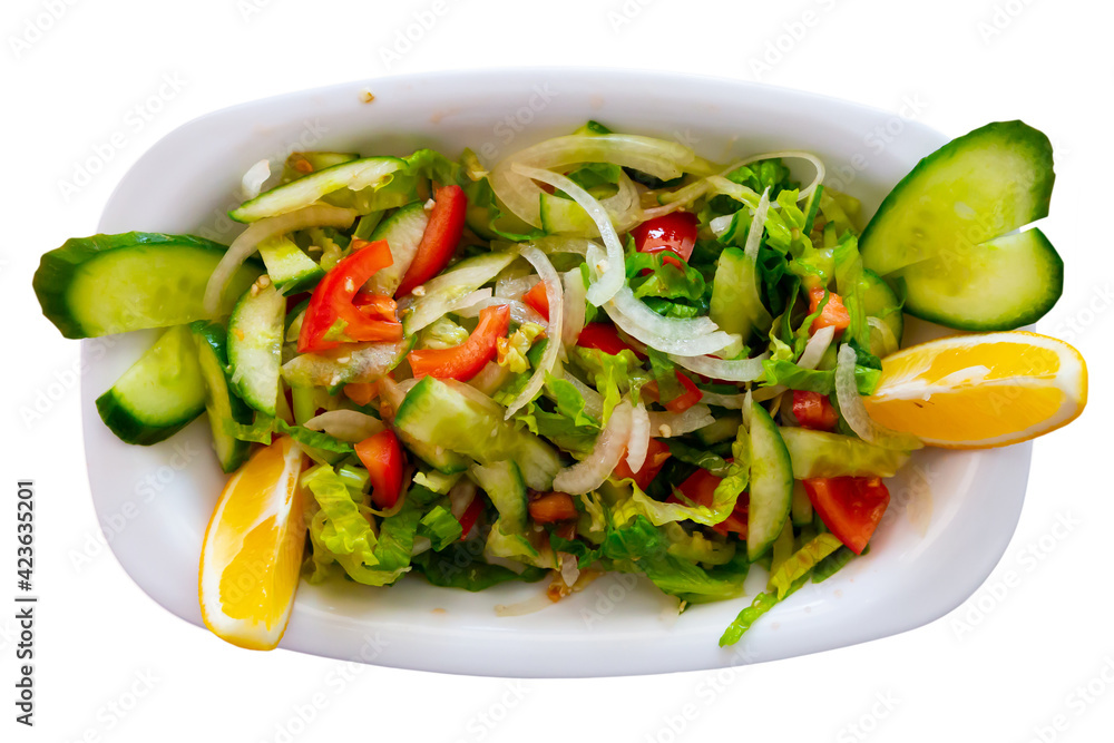 Traditional Turkish vegetable salad Coban salatasi from chopped tomatoes, cucumbers, greens and onions served with lemon slice. Isolated over white background.