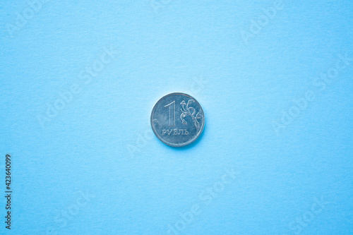 Coin one rouble on bright blue background. ruble depreciation. Rouble to dollar