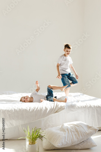 Indoor positive activity. Small children jumping on a bed and having fun in sunshine