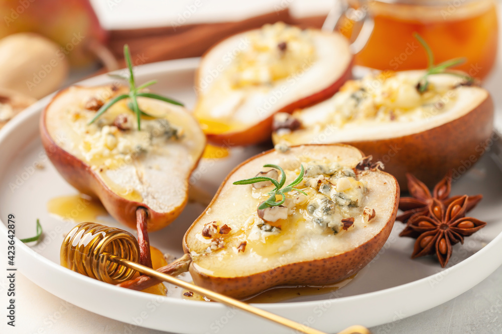 Baked pears with cheese, nuts and honey in a plate on the table.
