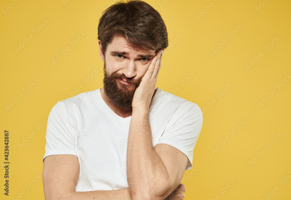 Emotional brunette man gestures with his hands on a yellow background Emotional brunette man gestures with his hands on a yellow background
