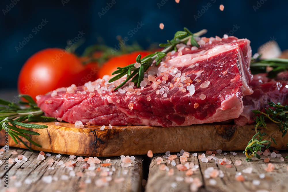 fresh steak with beef salted on a background of ingredients, frozen in motion on a blue background fresh steak with beef salted on a background of ingredients, frozen in motion on a blue background