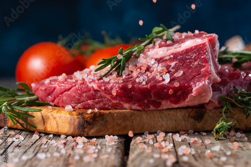 fresh steak with beef salted on a background of ingredients, frozen in motion on a blue background