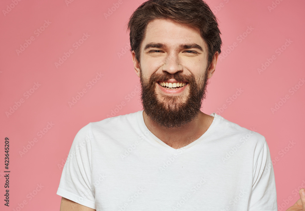 Portrait of a happy man with a beard on a pink background in a white T-shirt Portrait of a happy man with a beard on a pink background in a white T-shirt