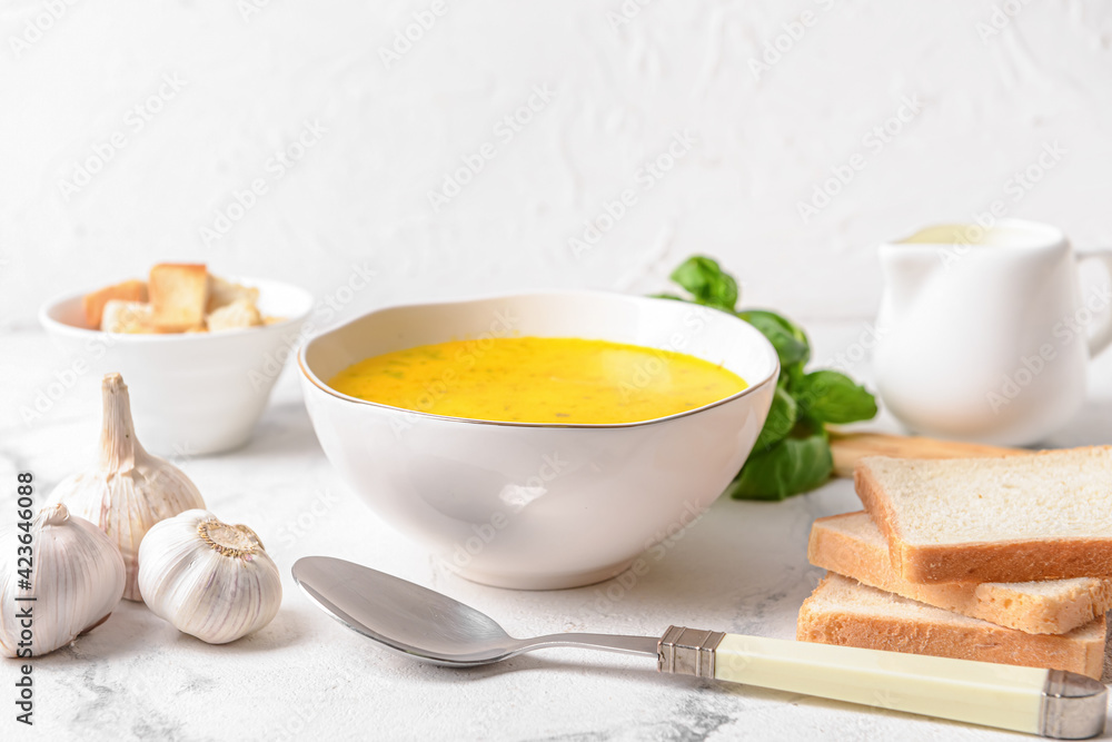 Bowl with tasty garlic cream soup on light background