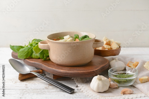 Bowl with tasty garlic soup on light wooden background