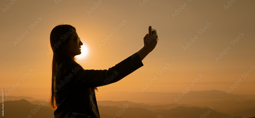 Silueta de mujer delgada tomándose selfie con celular en atardecer en las montañas del cerro de la bufa Vallarta Jalisco