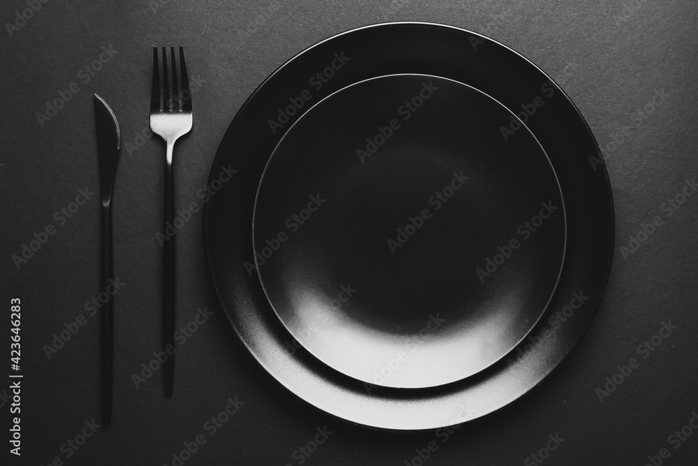 Plates and cutlery on dark background Plates and cutlery on dark background