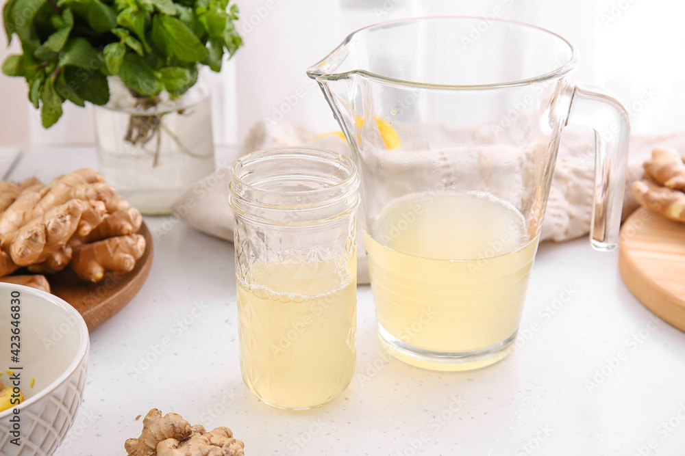 Jug and glass of healthy ginger juice on table Jug and glass of healthy ginger juice on table