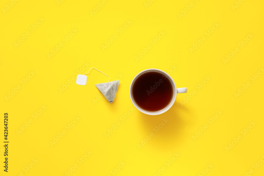 Cup of hot beverage and tea bag on color background - obrazy, fototapety, plakaty 