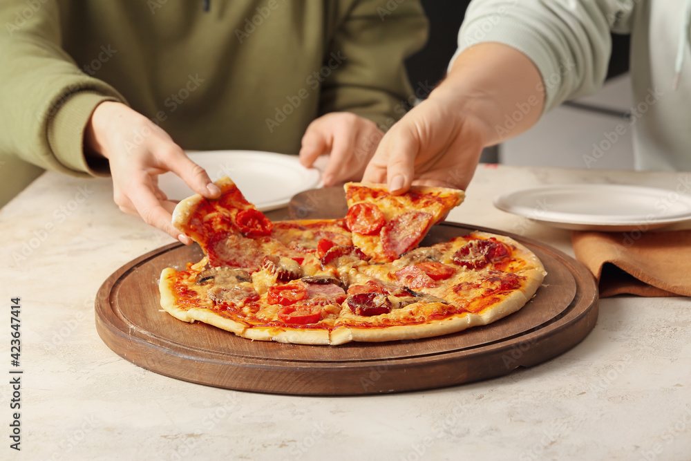 Women eating tasty pizza at table